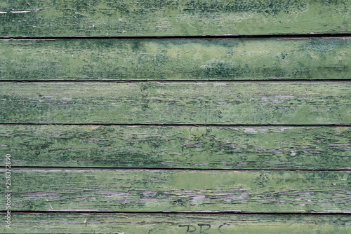 Macro texture of a wooden fence with cracked green paint.