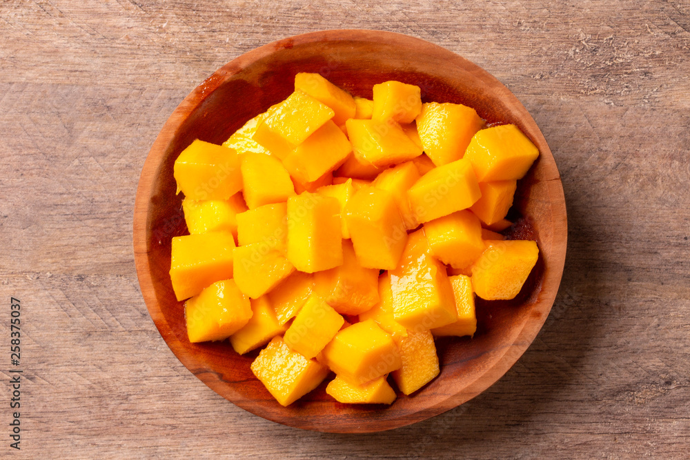 Mango fruit and mango cubes on the wooden table. Mango fruit and mango cubes on the wooden table.