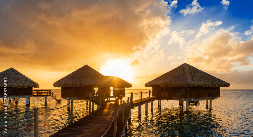 Walking Way to Water Bungalows with a idyllic Sunset, beautiful Sky and Clouds in the Lagoon Huahine, French Polynesia.  Copy space for text.