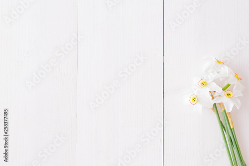 Flat lay composition with white daffodils on a white wooden table