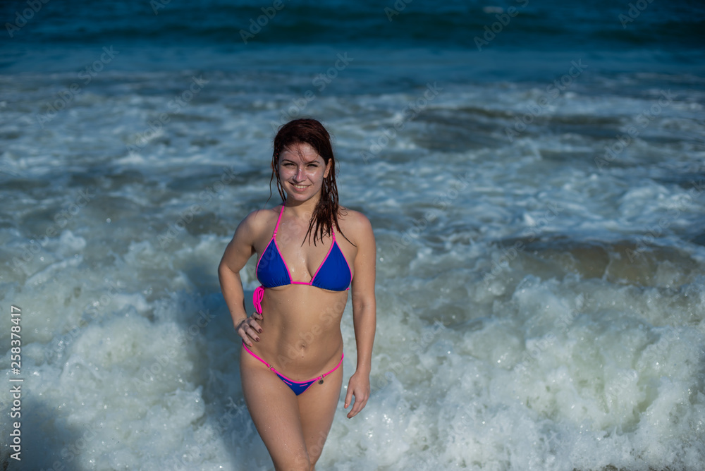 beautiful young woman in a seductive bikini comes out of the sea with high waves. Big waves in the ocean beautiful young woman in a seductive bikini comes out of the sea with high waves. Big waves in the ocean