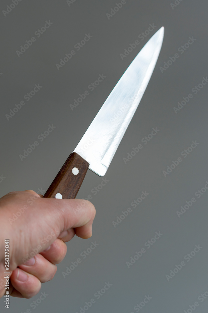 Man's hand with a knife on gray background. Concept of violence. Hand of a gangster with a knife. vertical photo Man's hand with a knife on gray background. Concept of violence. Hand of a gangster with a knife. vertical photo
