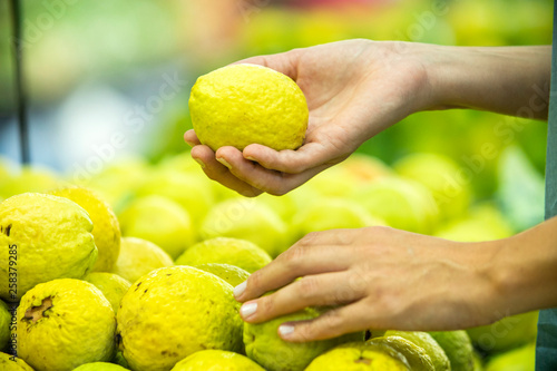 Woman's hand choosing guavas in supermarket