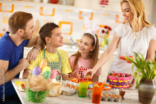 Woman with family preparing Easter basket with eggs