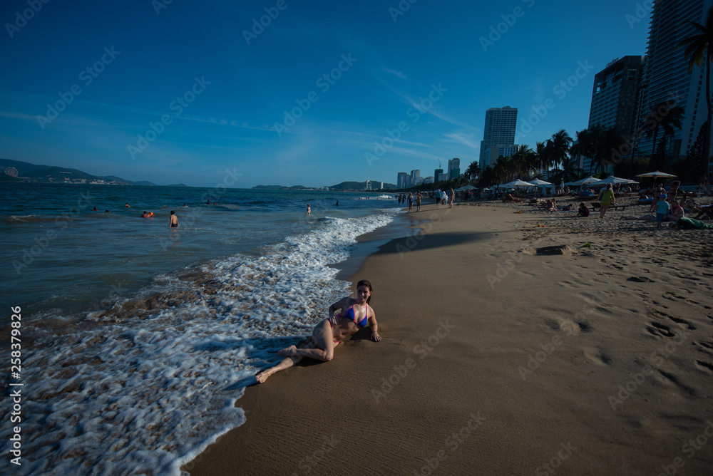 A young woman in a seductive bikini lying on the beach. Girl lying on the sand by the ocean A young woman in a seductive bikini lying on the beach. Girl lying on the sand by the ocean