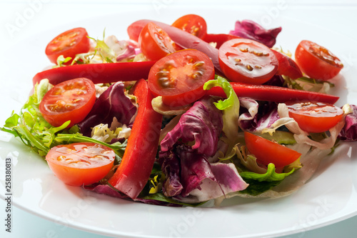 Salad with fresh vegetables on a white table