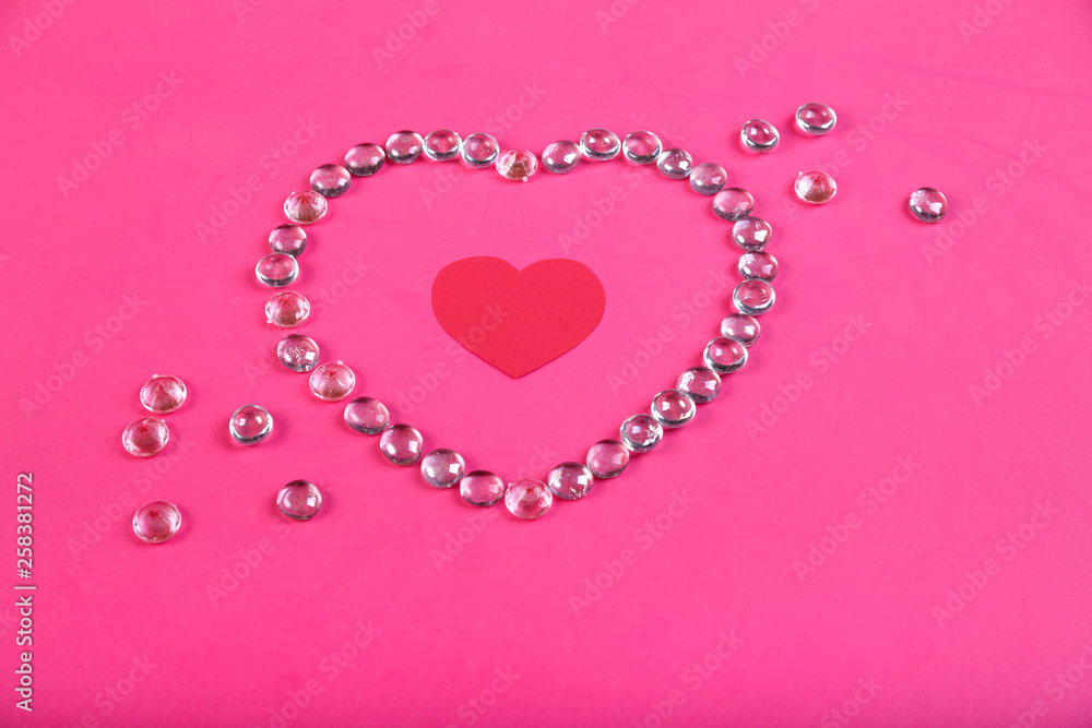 A heart lined with beads on a pink background with a heart in the middle in a frame of beads.