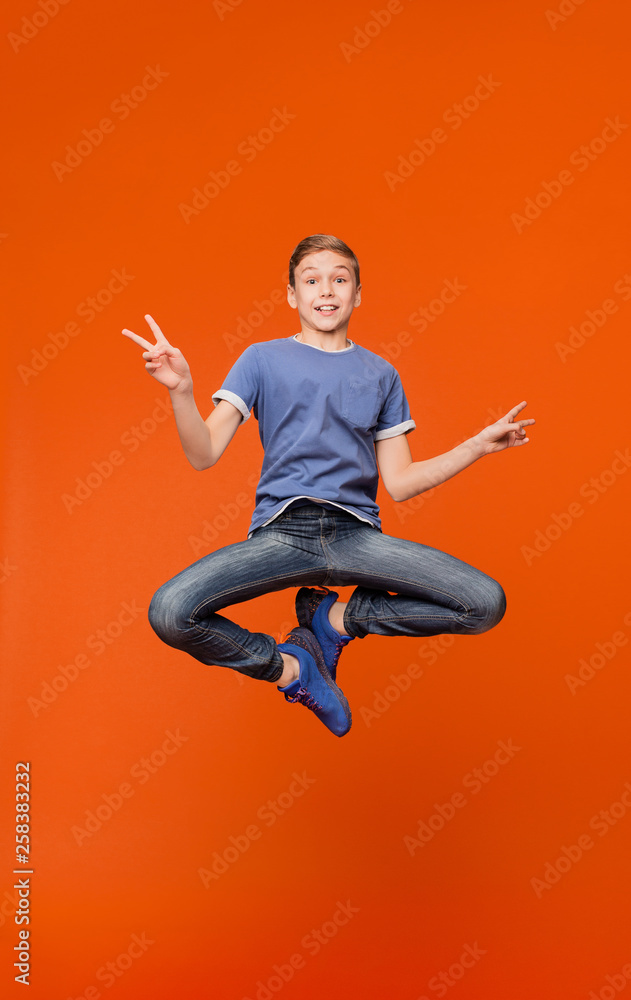 Cute boy jumping and gesturing peace signs