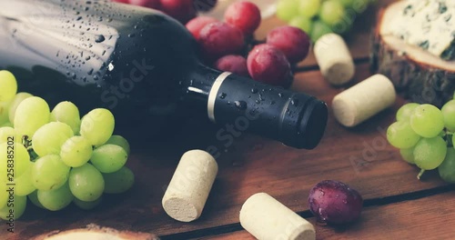 red wine bottle with grapes on old wooden background