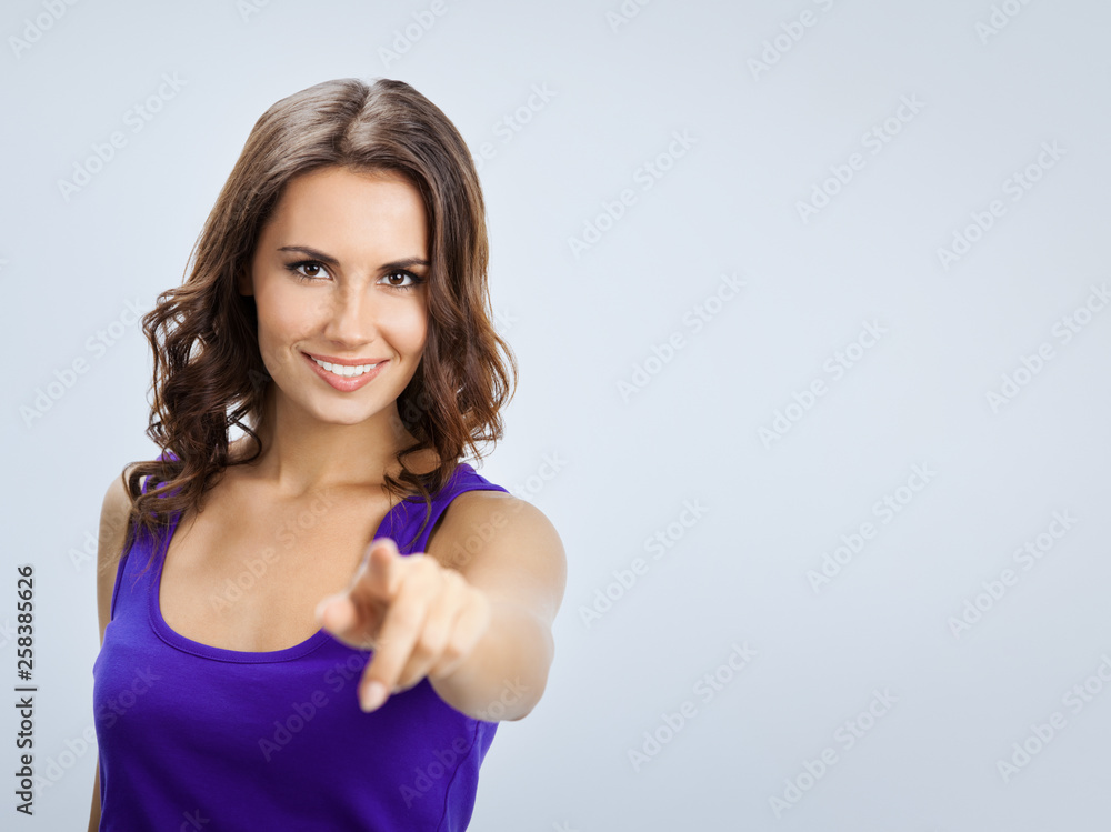 Woman pointing at something or pressing virual button, on grey Woman pointing at something or pressing virual button, on grey