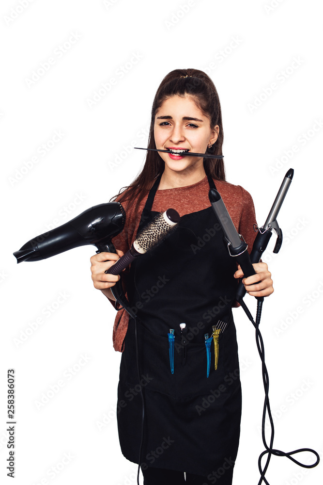young girl hairdresser with a curling iron, hairdryer, comb in teeth.