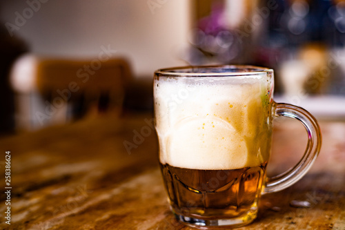 Beer with foam on the wooden table in the kitchen