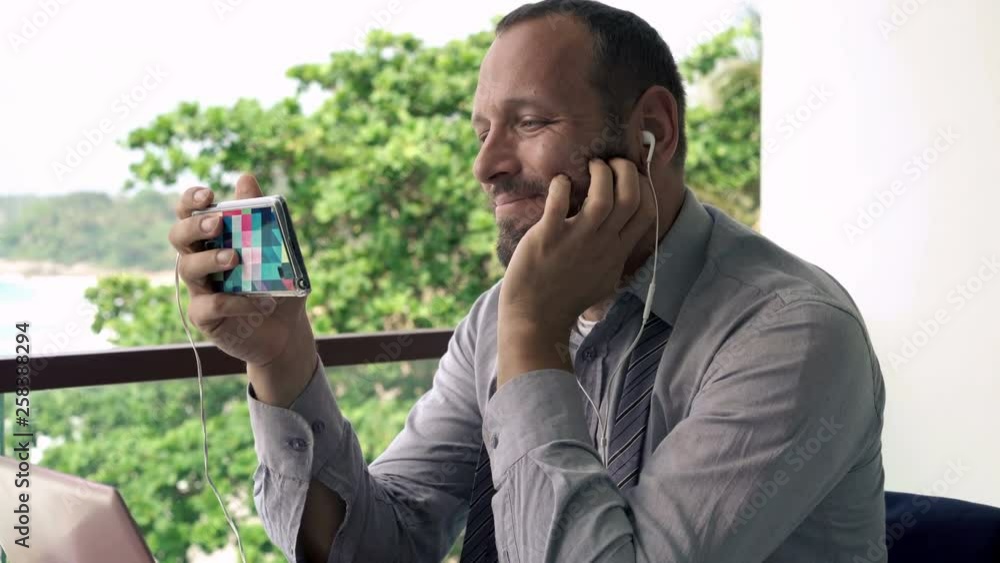 Young businessman watching movie on smartphone on terrace, with sea view, 4K Young businessman watching movie on smartphone on terrace, with sea view, 4K