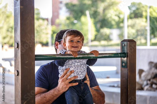 A beautiful child plays in a bar helped by his father photo