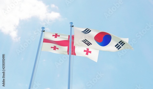 Georgia and South Korea, two flags waving against blue sky. 3d image