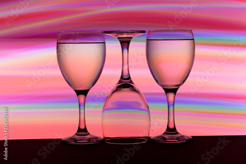 Three wine glasses in a row with colorful light painting behind