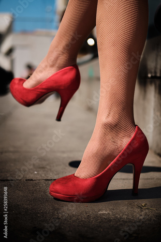 Legs of young girl with red high-heeled shoes