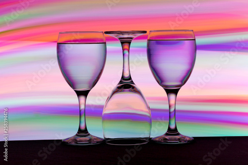 Three wine glasses in a row with colorful light painting behind