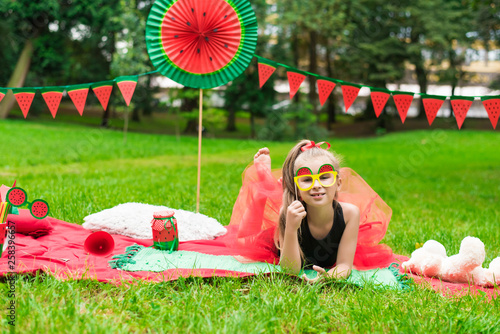 Watermelon party, picnic for children in park. watermelon day. Cute small girl with glasses. © MartaKlos