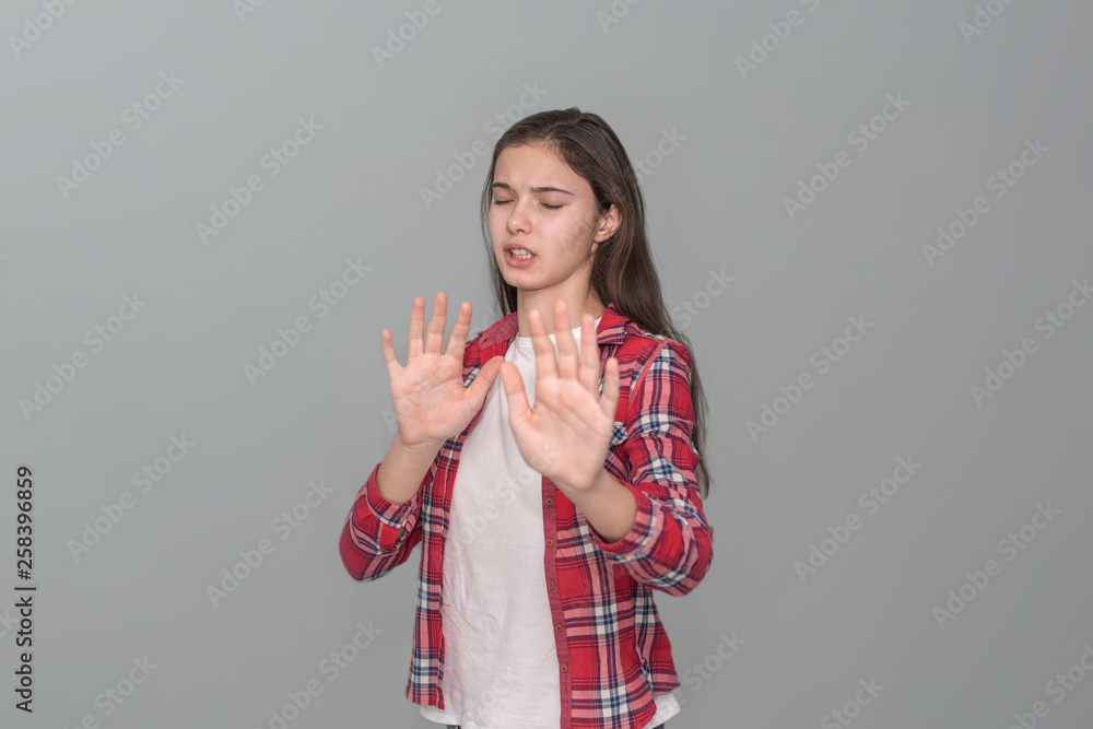 young girl put her hands in front of her, a gesture of refusal, gray wall background young girl put her hands in front of her, a gesture of refusal, gray wall background