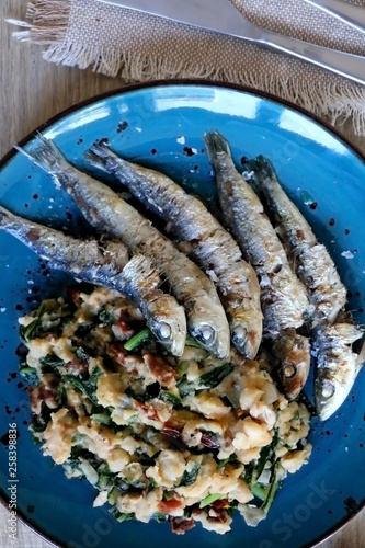 Grilled sardines and salad made with chicory, white beans and dried tomatoes. Selective focus. 