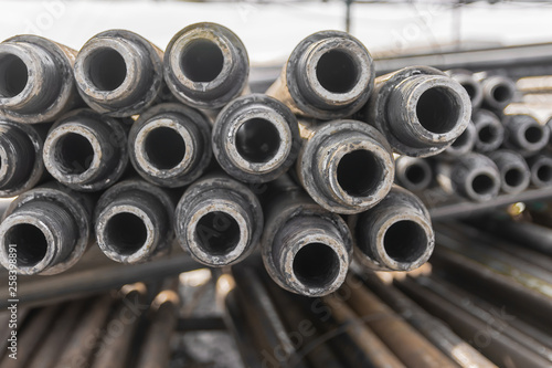 Drill pipes for drilling oil and gas wells are located horizontally on the rack. In the foreground is a threaded pipe joint. In the background is a blurred image of the other pipes.