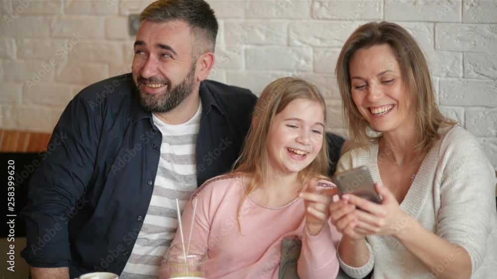Happy Mother, Father And Little Girl Having Fun And Taking Selfie By Smartphone at Cafe. Happy Mother, Father And Little Girl Having Fun And Taking Selfie By Smartphone at Cafe.