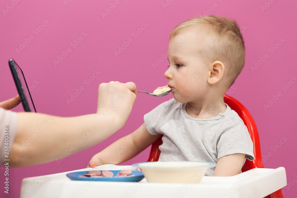 Cute little boy, eats breakfast at home, while watching cartoon on tablet. Cute little boy, eats breakfast at home, while watching cartoon on tablet.