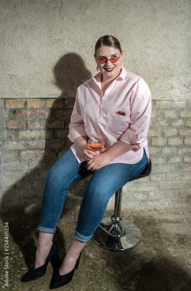 beautiful seductive girl plus size with glass prosecco, taking off her glasses. Concept: body positive, optics beautiful seductive girl plus size with glass prosecco, taking off her glasses. Concept: body positive, optics