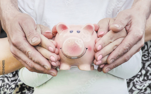 The child and parents are holding a piggy bank in their hands. Fotobehang
