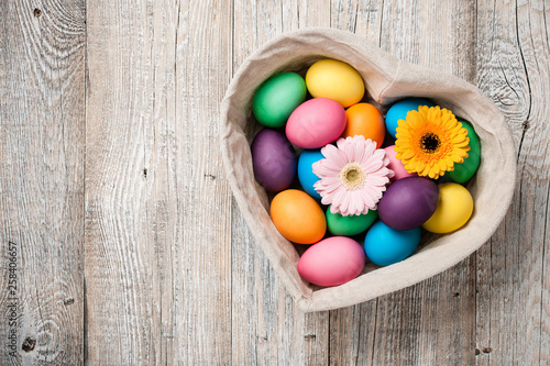 Easter eggs and gerbera flowers in heart shaped basket