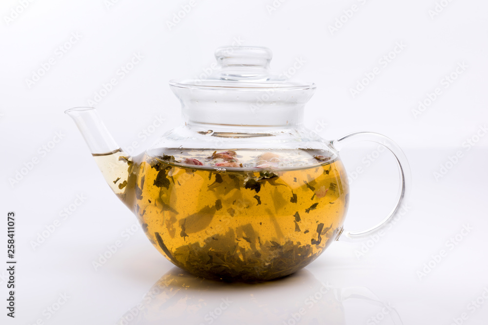 Glass teapot with herbal tea and roses isolated on white background Glass teapot with herbal tea and roses isolated on white background