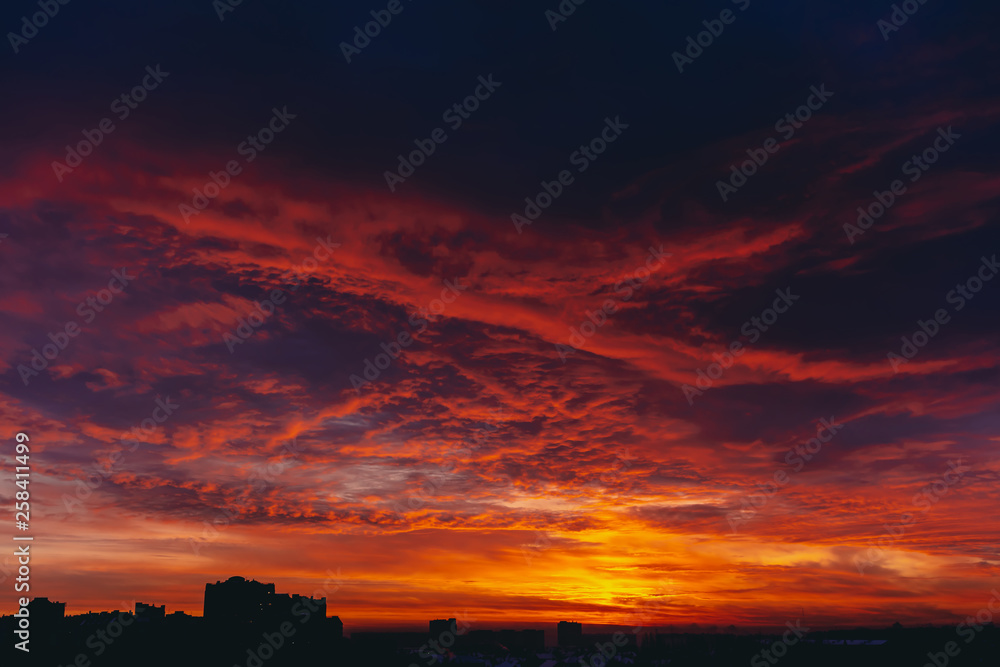 Fiery red blood vampire dawn. Amazing warm dramatic fire blue dark cloudy sky. Orange sunlight. Atmospheric background of sunrise in overcast weather. Hard cloudiness. Storm clouds warning. Copy space
