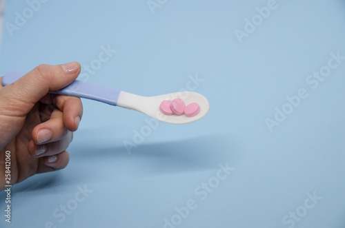 Medical pink pills in a spoon