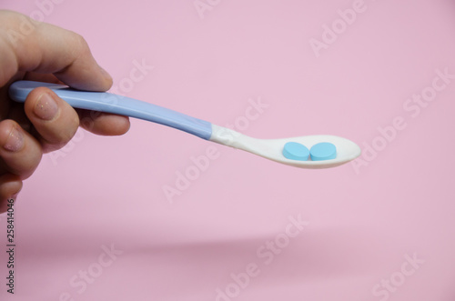 Medical blue pills in a spoon