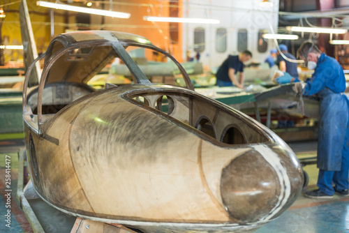 people in blue robes build a plane in the factory. Workers in overalls working on the details of the aircraft. photo