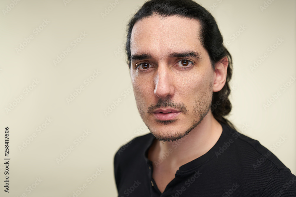 Portrait of latino handsome man with long black hair and black t shirt in studio Portrait of latino handsome man with long black hair and black t shirt in studio