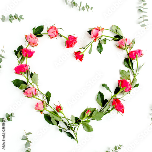 The heart is lined with red roses on white background. Valentine's background. Floral pattern. Flat lay, top view.