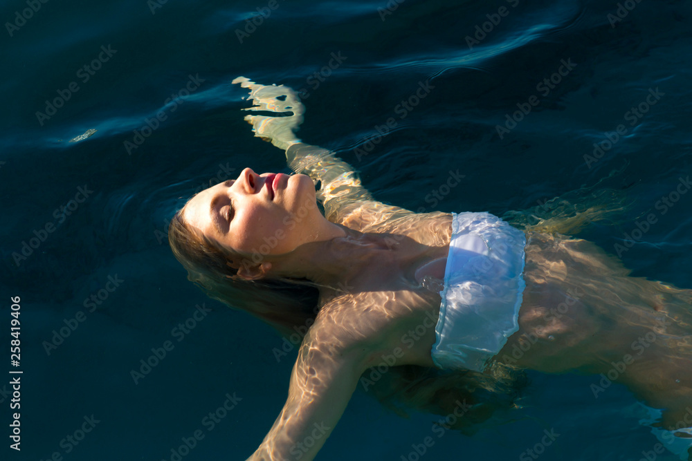 Young girl swimming on her back - obrazy, fototapety, plakaty 