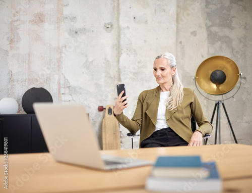 Businesswoman looking at cell phone in office photo