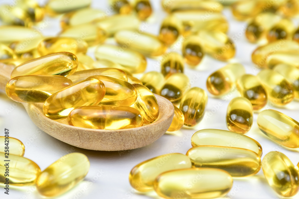 close up of Fish oil capsules in wood spoon. Supplementary food. Vitamin E. Vitamin D. close up of Fish oil capsules in wood spoon. Supplementary food. Vitamin E. Vitamin D.