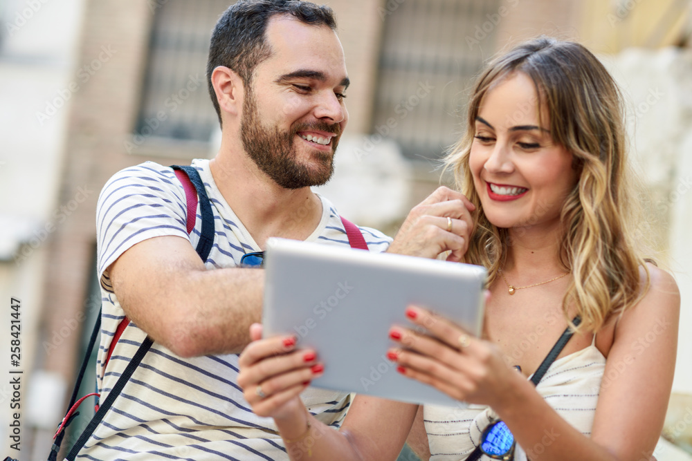 Spain, Andalusia, Malaga, happy tourist couple in the city looking at tablet Spain, Andalusia, Malaga, happy tourist couple in the city looking at tablet