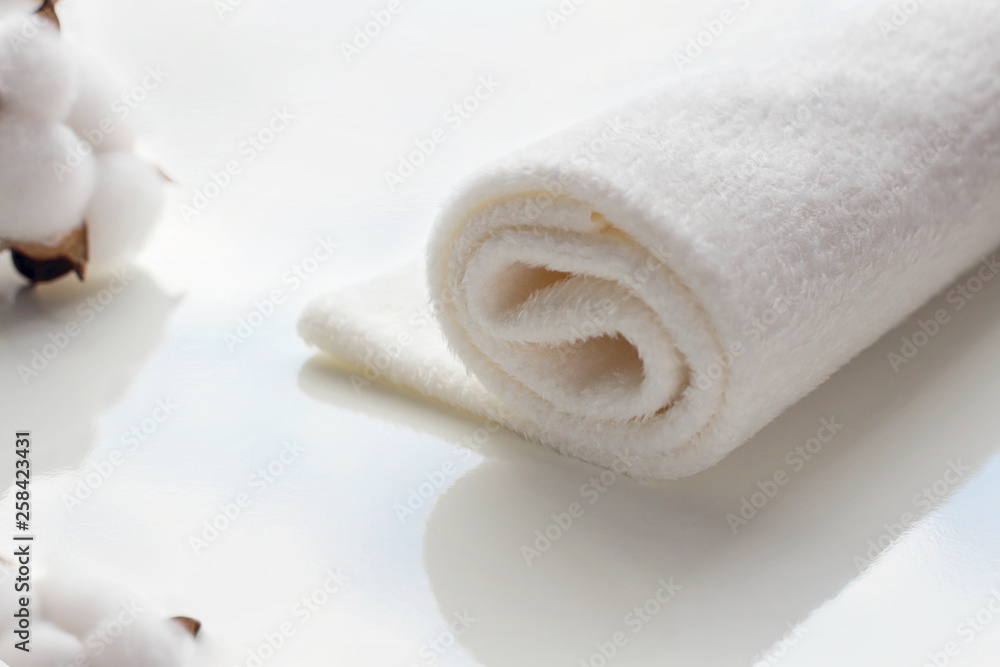 On a white table, a sprig of cotton flowers and a soft cloth. On the surface of the table - a reflection of blue sky and clouds. Selective focus, copy space. On a white table, a sprig of cotton flowers and a soft cloth. On the surface of the table - a reflection of blue sky and clouds. Selective focus, copy space.