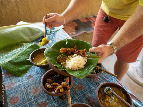 Tableau sur toile Male hands with rice and curry served in traditional rural kitchen