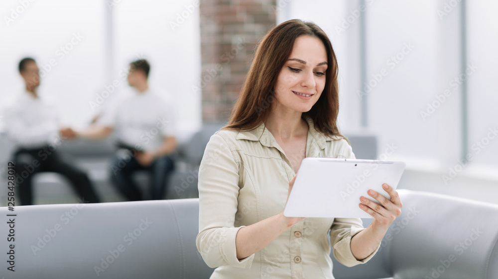 business woman with digital tablet sitting on sofa in office lobby business woman with digital tablet sitting on sofa in office lobby