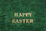Happy Easter gold text laying in green grass