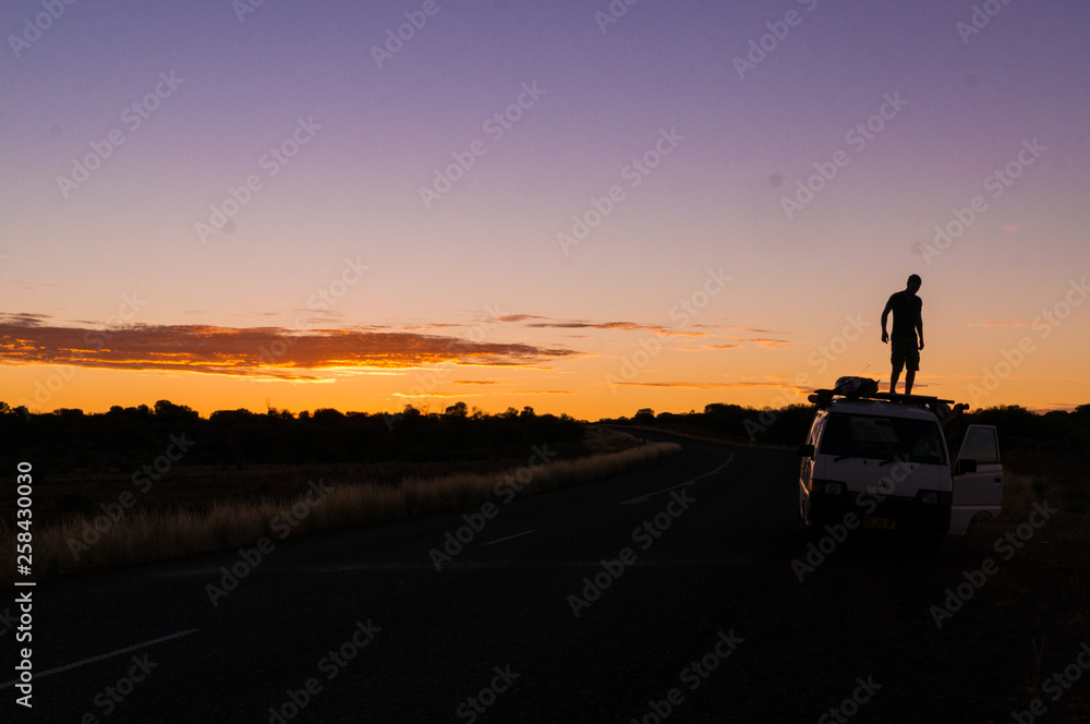 young man standing on car while a nice Sunset in the Outback of Australia, northern terrotory