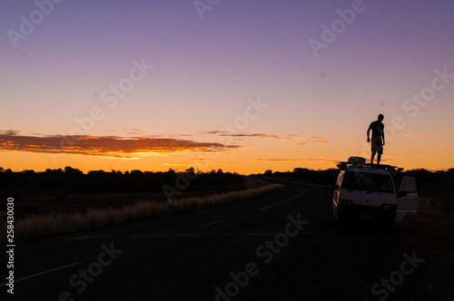 young man standing on car while a nice Sunset in the Outback of Australia, northern terrotory