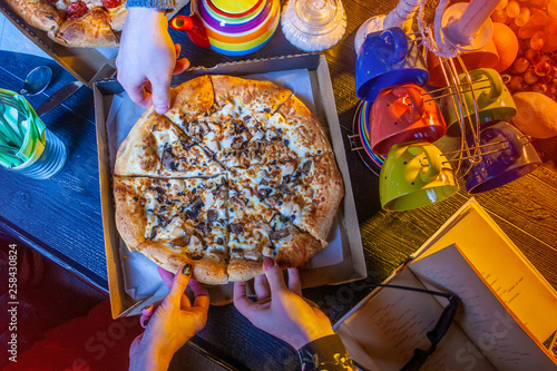 Pizza on the table. Hands t...