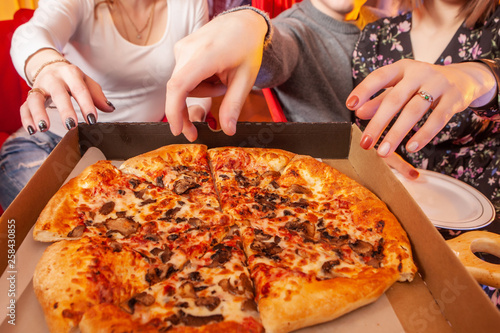 Three people take pizza. Pi...